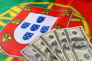 Portuguese flag with American dollars in front on a flat surface