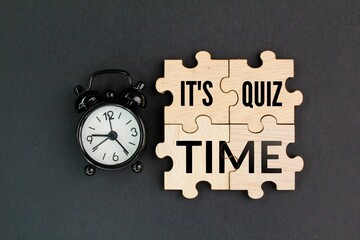 bell clock and wooden puzzle with the word Its Quiz Time. the concept of answering quizzes or quiz...