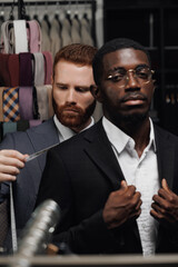 Tailor measuring Young man African American businessman for bespoke suit in tailoring studio