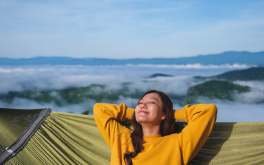 Portrait of a young woman lying and relaxing on hammock with mountain views and sea of fog