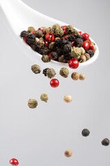 Different types of peppercorns pouring. Red, green, white and black pepper.