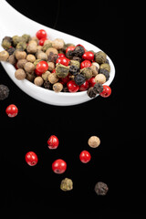 Different types of peppercorns pouring. Red, green, white and black pepper.