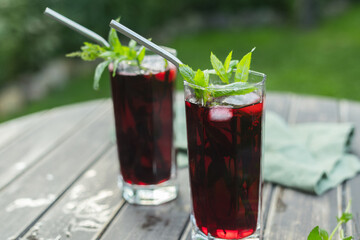 Summer cocktails. Two glasses with iced red hibiscus tea on table outdoors