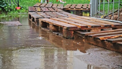 Wooden Transport Cargo Pallets Used as Temporary Pedestrian Walkway on Flooded Sidewalk after Heavy Rain