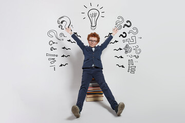 Thinking child boy on white background with light bulb and question marks. Brainstorming and idea concept