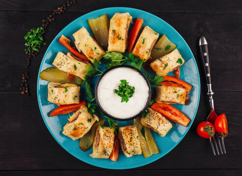 Turkish beyti kebab with vegetables and yogurt sauce on turquoise plate