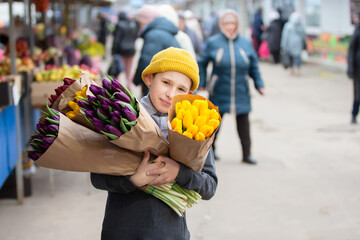 The boy holds a bouquet of flowers and smiles. Flowers come in a variety of colors, including...
