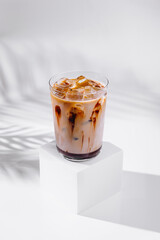 Iced coffee drink standing on white cube with chocolate syrup