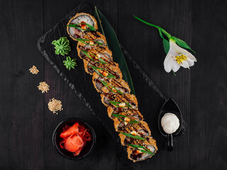 Tempura maki sushi roll pieces lying on black stone plate