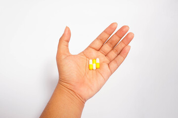 a man consuming three yellow capsules with white isolated