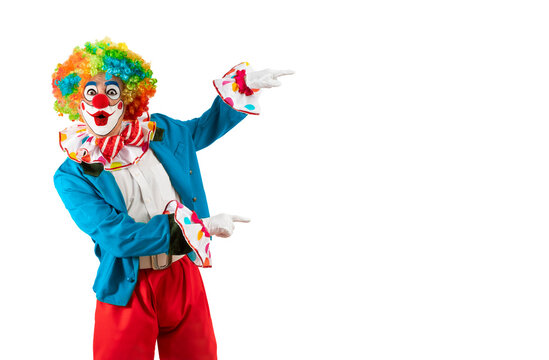 Surprised clown pointing at blank template copy spase for advertising, posters, greetings, invitations. Entertainer as Joker in a suit and wig, with clown whiteface makeup.