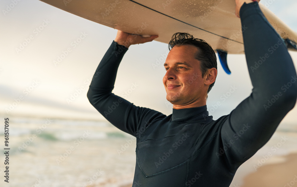 Wall mural smiling surfer carrying his surfboard on the beach during sunset, ready to hit the waves. concept of