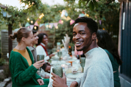 Side view portrait of smiling young man having fun with friends at party in back yard