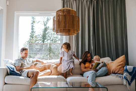 Family spending leisure time while sitting on sofa in living room at home