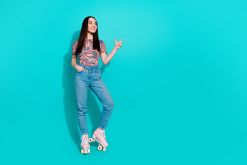 Full length photo of adorable lovely girl wear striped t-shirt riding rollers pointing empty space isolated teal color background