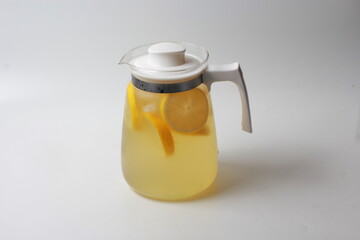 lemonade with ice with a glass jug on a white background.
