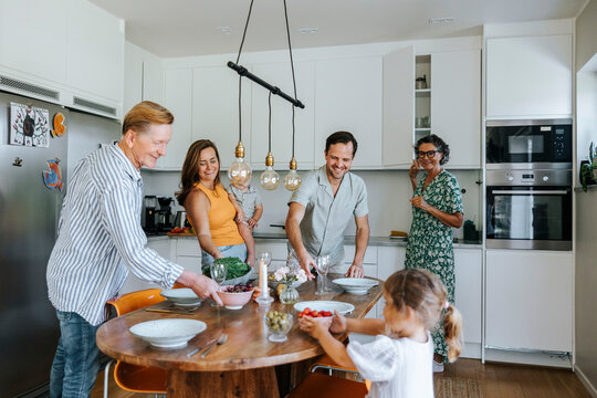 Happy multi-generational family helping each other in setting dining table at home
