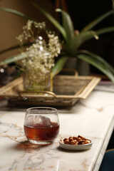 Glass with alcohol and ice cube. Cocktail with gin, brandy and roasted nuts