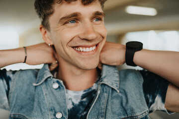 Happy young man with tattooed arm adjusting collar of jacket