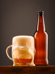 A bottle of beer and a glass of beer on a dark background.