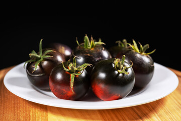 Cumato black tomatoes in a white plate. Black tomato.