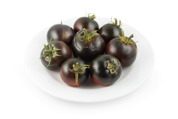 Ripe tomatoes in a white plate on a white background. Black tomatoes. Cumato tomatoes