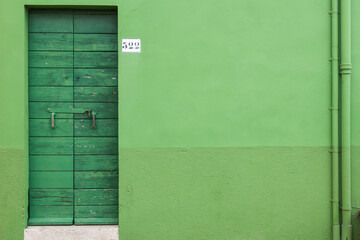 A green door on a green wall in the island of Burano, Venice, Italy.