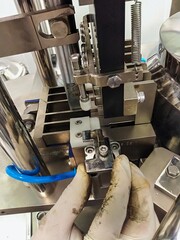 a close-up of the hands of a maintenance worker working on a machine (capsule filler) in a production facility in a pharmaceutical industry