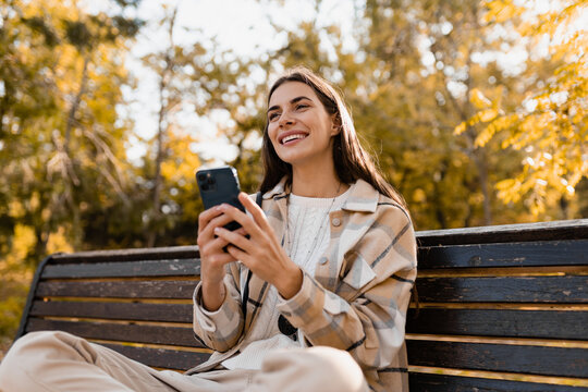 attractive young woman walking in autumn wearing jacket using phone - Powered by Adobe