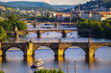 Aerial view of Charles Bridge in Prague with the Vltava River and crowds of tourists at the golden...
