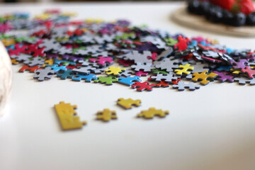 Colorful jigsaw puzzle pieces, cup of tea or coffee, eyeglasses and fresh berries for snacking....