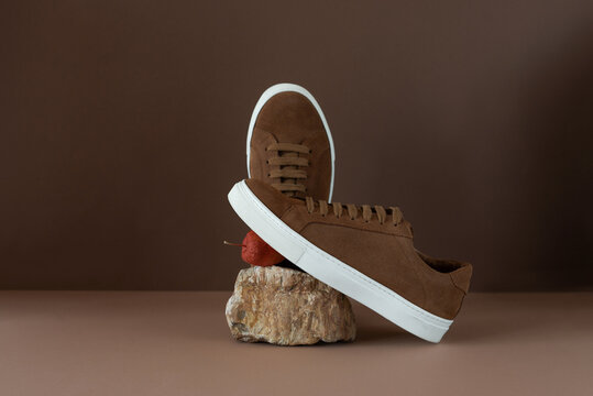 Still life of brown men's minimalist boots with white sole on beige and brown background. Autumn concept