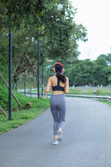 young Asian woman wears sports bra and running shoes to go jogging every morning for her health because running can help her body burn extra energy. Health running concept for the body.