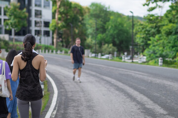 Asian woman wearing sports bra walking along path by reservoir in morning because walking is way to warm up body and muscles ready for running. warming up body to be ready for running by walking