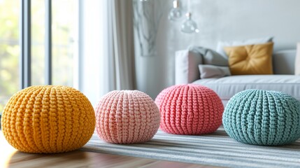 A minimalist living room featuring four pastel-colored knitted poufs in yellow, pink, mint, and pale peach arranged on a striped rug. The soft tones create a serene and calm atmosphere, perfect for