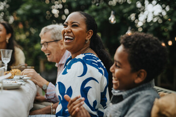 Cheerful mid adult woman having fun with male family members at lunch party