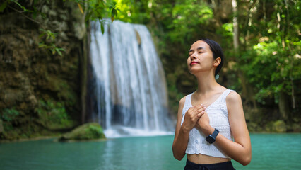 Woman traveler happy at deep forest waterfall. Erawan Waterfall National Park, Kanchanaburi, Thailand.