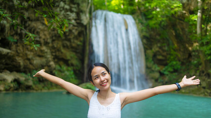 Fototapeta premium Woman traveler happy at deep forest waterfall. Erawan Waterfall National Park, Kanchanaburi, Thailand.