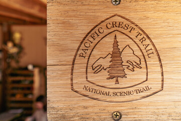 A wooden sign with a tree on it that says Pacific Crest Trail