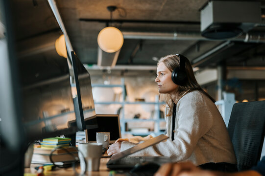 Focused young computer programmer doing coding while sitting at desk in office
