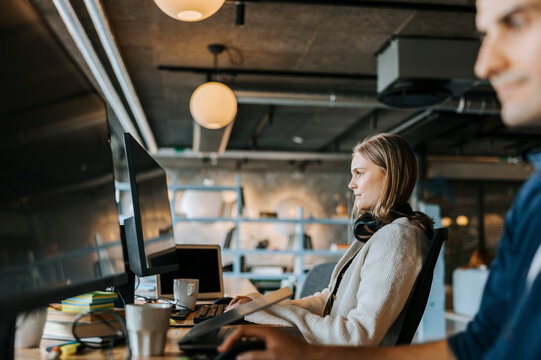 Young female programmer doing coding while sitting at desk in office