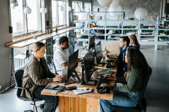 Male and female entrepreneurs sitting at desk and working at coworking office