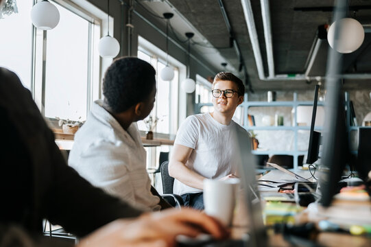 Male programmer talking with colleague while working in tech startup office