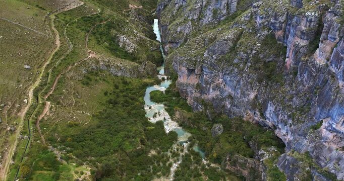 Beautiful zoom in drone shot taken at Millpu lake with turquoise waters located in Ayacucho, Peru with mountains and vegetation around.