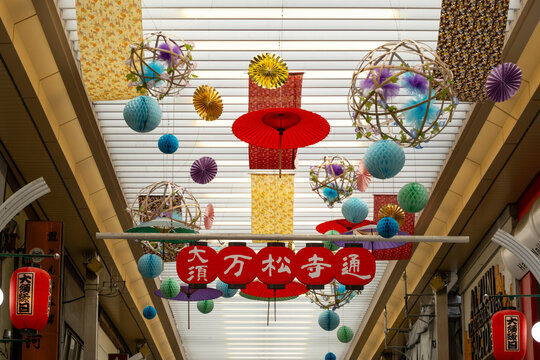 Sign of Osu Banshoji Shopping Street with colorful and festive decorations hanging over a shopping arcade. Nagoya, Japan. 大須万松寺通