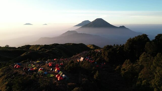 Aerial views of Mount Sindoro and Mount Sumbing in the distance from peak of Mount Prau, Dieng, Wonosobo, Indonesia with soft mist on the mountain slopes at dawn.