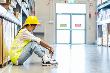 Young asian woman warehouse worker staff feeling sad and upset or look tired and lost job while sitting on the floor of the storehouse due to been fired from job cause by company bankruptcy