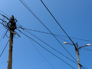 A tangled web of power lines against a clear blue sky
