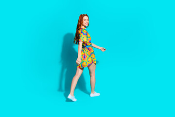Full body photo of attractive young woman walking turn around dressed stylish colorful clothes isolated on cyan color background