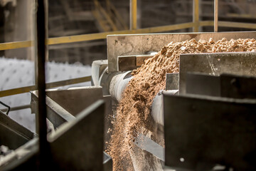 Cement factory. A conveyor with stones and gravel undergoes the crushing process. Modern...